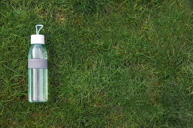 Photo of Bottle of water on green grass, top view with space for text. Morning exercise