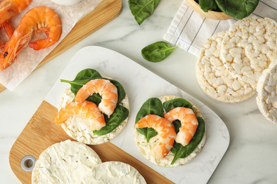 Crunchy rice cakes with shrimps and basil on white marble table, flat lay