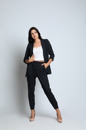 Full length portrait of beautiful woman in formal suit on light background. Business attire