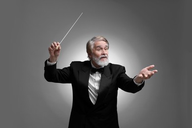 Photo of Professional conductor with baton on grey background