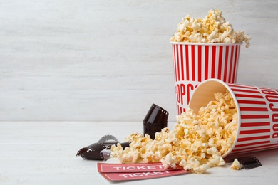 Popcorn, tickets and film footage on white wooden table, space for text. Cinema snack