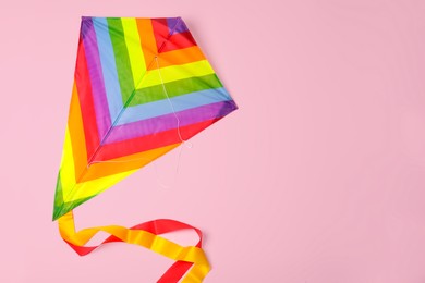Bright rainbow kite on pink background, top view. Space for text