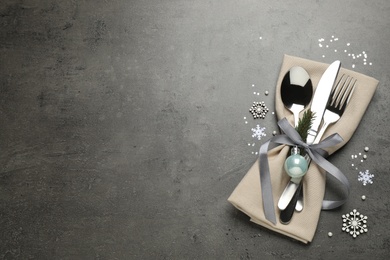 Cutlery set and festive decor on grey table, flat lay with space for text. Christmas celebration