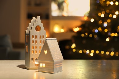 Photo of Beautiful house shaped candle holders on table indoors, space for text. Bokeh effect