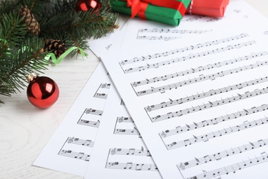 Composition with Christmas music sheets with notes on white wooden background, closeup
