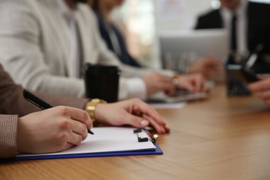 Woman writing at table during business meeting, closeup. Management consulting