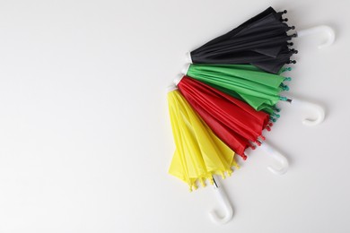 Small color umbrellas on white background, top view. Space for text