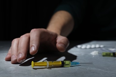 Photo of Addicted man and syringe on grey marble table, closeup. Hard drugs