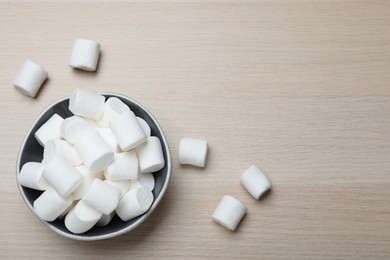 Delicious puffy marshmallows on wooden table, flat lay. Space for text