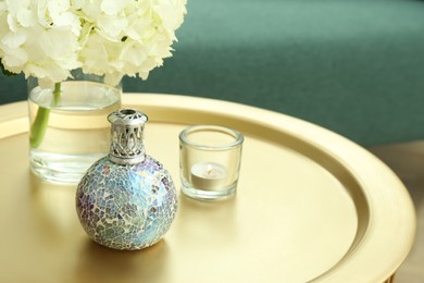 Stylish catalytic lamp with burning candle and hydrangea on golden table in living room, space for text. Cozy interior
