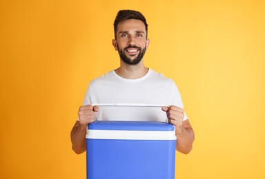 Happy man with cool box on yellow background
