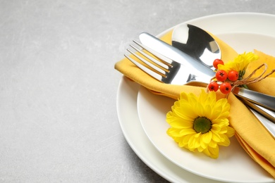 Closeup view of seasonal table setting with autumn flowers and ashberries on light grey background, space for text. Thanksgiving Day