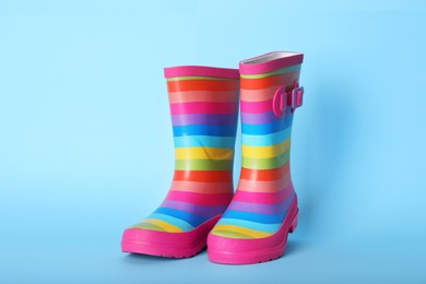 Pair of striped rubber boots on light blue background