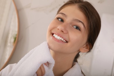 Beautiful teenage girl wiping face with towel at home, closeup