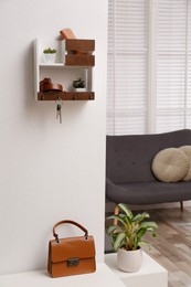 Hallway interior with stylish furniture, accessories and wooden hanger for keys on white wall
