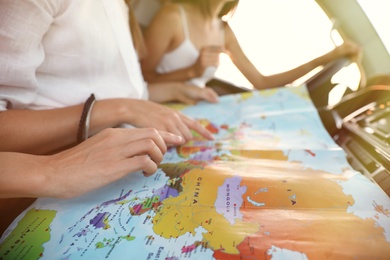 Group of friends with map in car on road trip, closeup