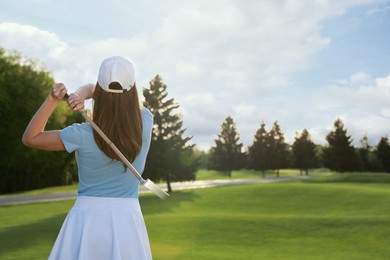 Woman playing golf on green course, back view. Space for text