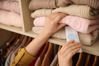 Photo of Woman putting scented sachet in wardrobe, closeup