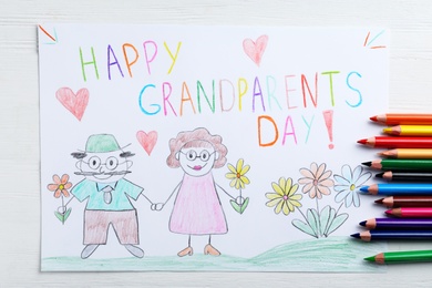 Beautiful drawing with phrase Happy Grandparents Day on white wooden table, flat lay