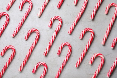 Sweet Christmas candy canes on grey background, flat lay