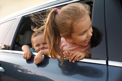 Happy little kids looking from family car outdoors