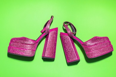 Photo of Fashionable punk square toe ankle strap pumps on green background, flat lay. Shiny party platform high heeled shoes