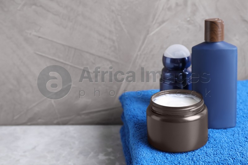 Cosmetic products and towel on light grey marble table, space for text. Men's hygiene