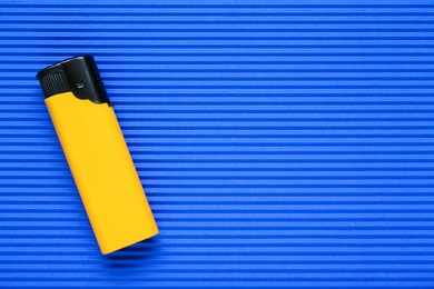 Photo of Stylish small pocket lighter on blue corrugated fiberboard, top view. Space for text