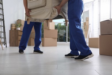 Moving service employees carrying armchair in room, closeup