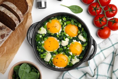 Photo of Flat lay composition with tasty green Shakshouka and ingredients on white table