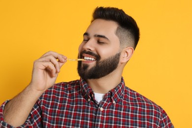 Young man eating French fries on orange background
