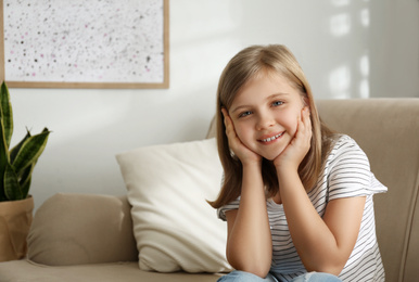 Cute little girl on couch at home. Space for text