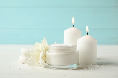 Photo of Spa composition with cream, candles and flowers on white table