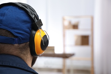 Worker wearing safety headphones indoors, closeup. Hearing protection device