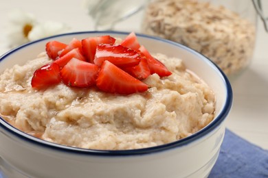 Tasty oatmeal porridge with strawberries on table, closeup