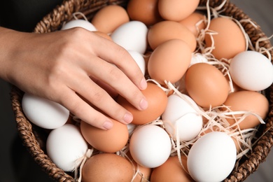 Woman with basket full of raw chicken eggs, closeup