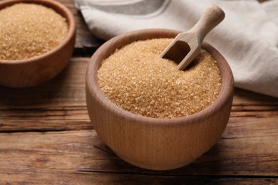 Photo of Brown sugar in bowls on wooden table, closeup