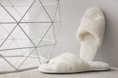 Soft fluffy white slippers near grey wall