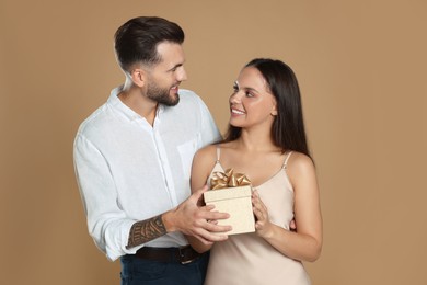 Lovely couple with gift on beige background