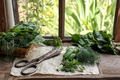 Different herbs and rusty scissors on window sill indoors