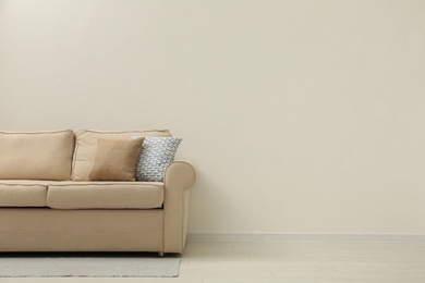 Comfortable sofa near beige wall in living room interior. Space for text