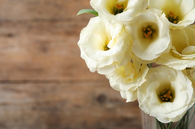 Beautiful white Eustoma flowers on wooden background, closeup. Space for text