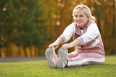 Happy mature woman stretching in park. Active lifestyle