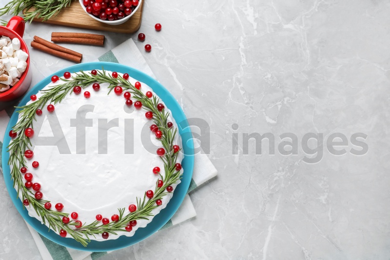 Photo of Traditional Christmas cake decorated with rosemary and cranberries on light grey marble table, flat lay. Space for text
