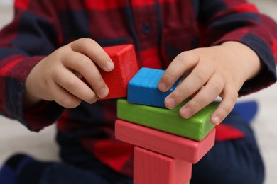Little child playing with building blocks indoors, closeup