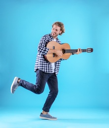 Young man playing acoustic guitar on color background