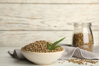 Bowl of hemp seeds on table against wooden wall