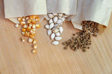 Different vegetable seeds on wooden table, flat lay