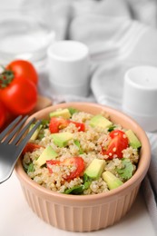 Photo of Delicious quinoa salad with tomatoes, avocado and parsley served on white table