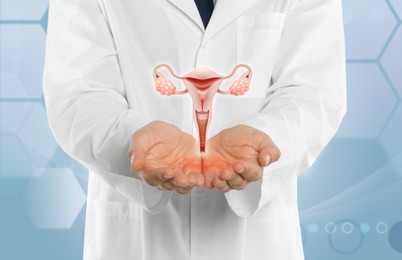 Doctor demonstrating virtual icon with illustration of female reproductive system on light background, closeup. Gynecological care 
